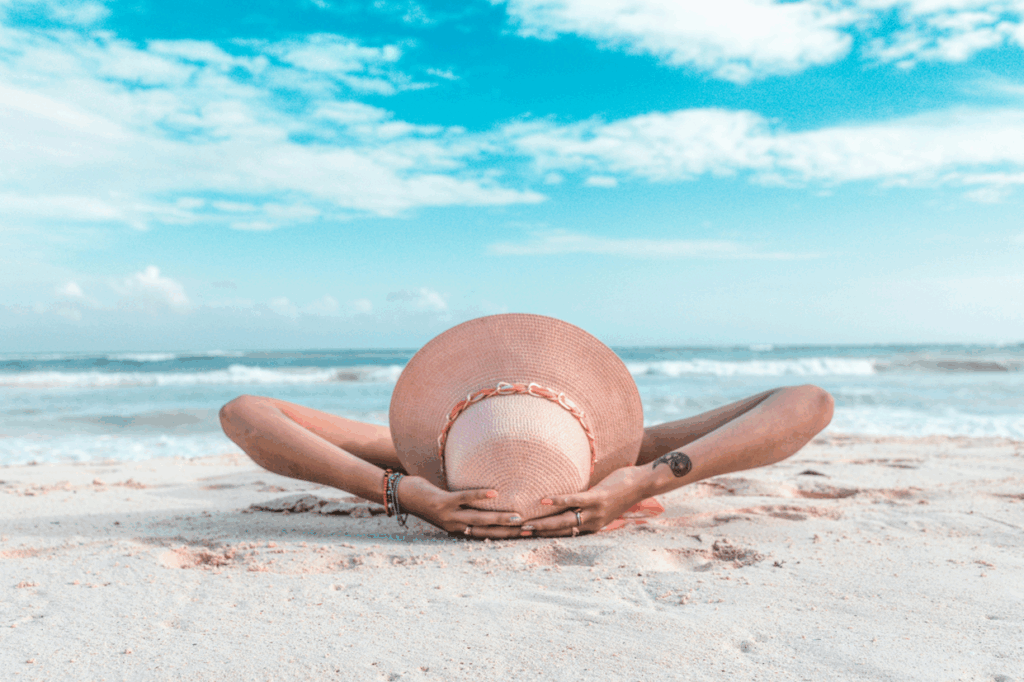 A person lying on the beach with their hands on their head after saving money on credit card interest